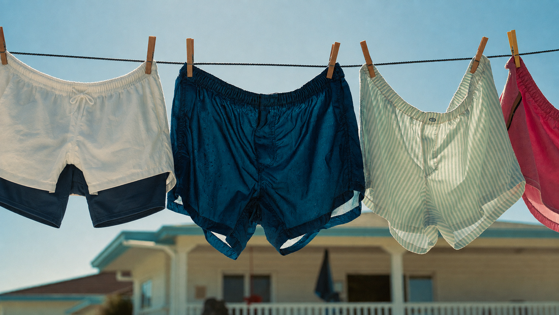 Wet swim shorts drying on a clothesline in summer sun
