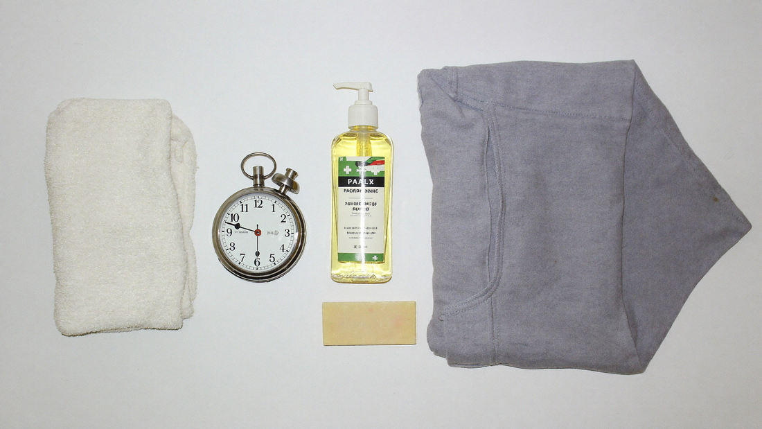 Stopwatch surrounded by petroleum jelly, mild soap, towel and loose shorts, a fast chafing relief kit